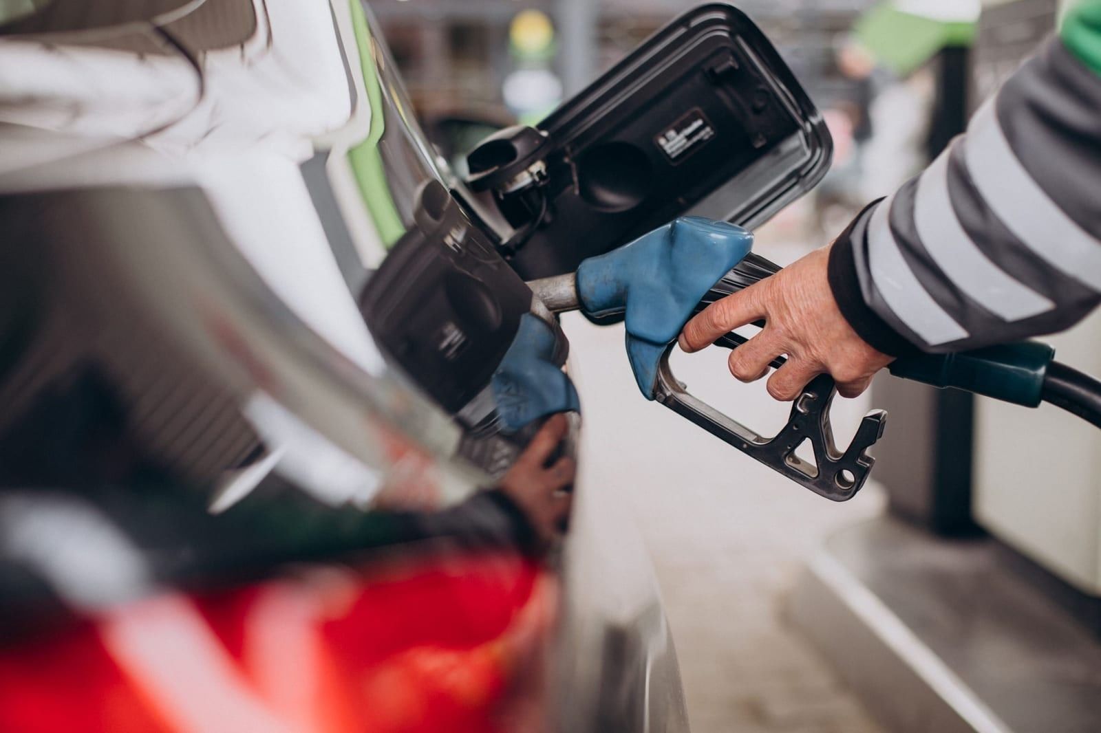 A driver filling up a car at a gas pump.
