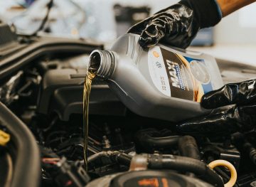 Hand pouring fresh oil into a car engine