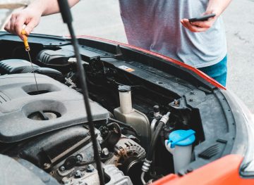 Person checking the engine oil using a dipstick