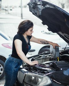 Woman pouring engine oil into a car engine.