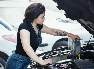 Woman pouring engine oil into a car engine.