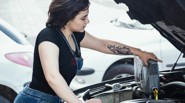 Woman pouring engine oil into a car engine.