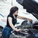 Woman pouring engine oil into a car engine.