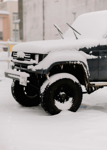 Left-Front quarter view of a black Jeep covered in snow.