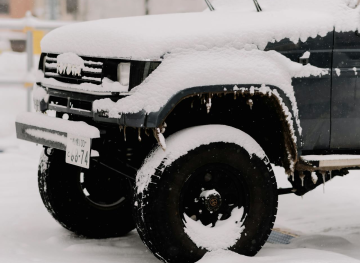 Left-Front quarter view of a black Jeep covered in snow.