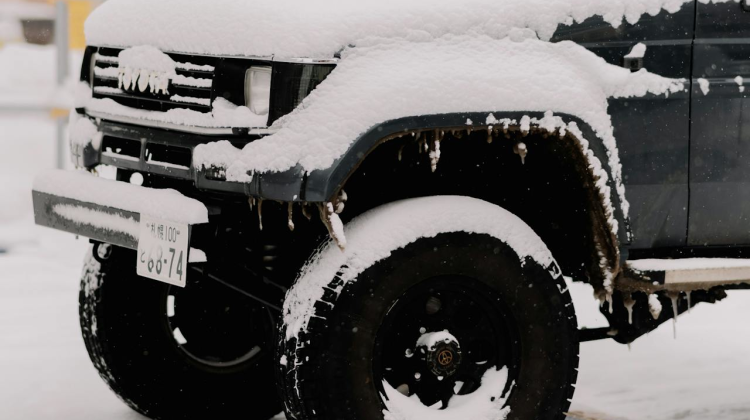 Left-Front quarter view of a black Jeep covered in snow.