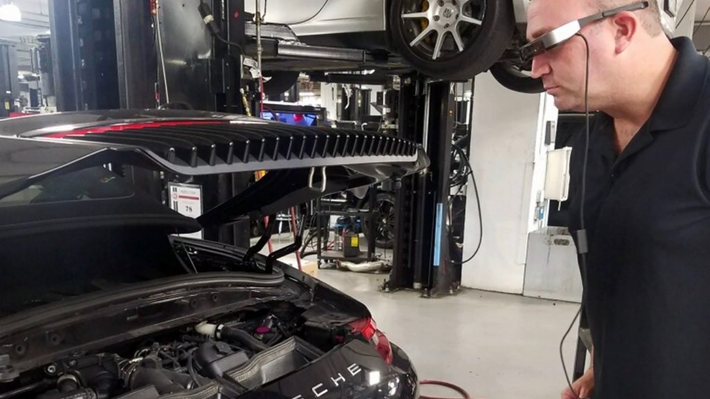 Mechanic inspecting car engine while wearing AR glasses