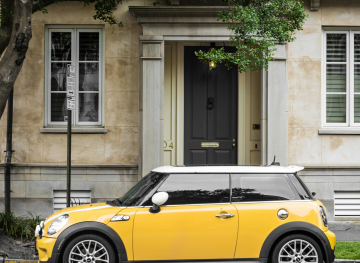 Yellow mini parked outside a rather posh looking residence.