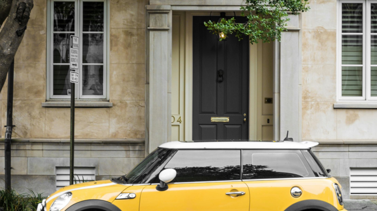 Yellow mini parked outside a rather posh looking residence.