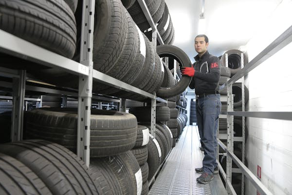 Tire technician removing a tire from a rack of new tires