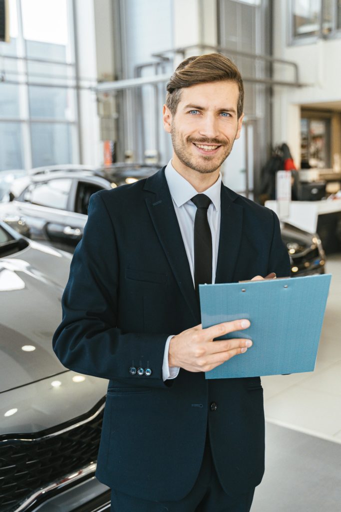 Car dealership showroom with sales person holding a clipboard